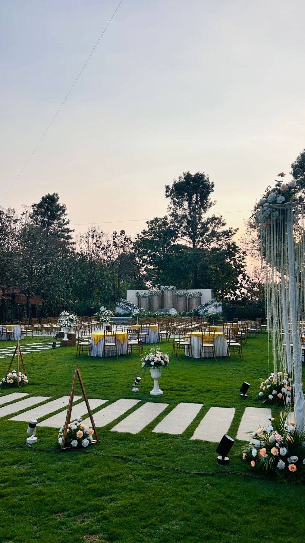 The lawn set with tables at dusk, the amphitheatre stage beyond